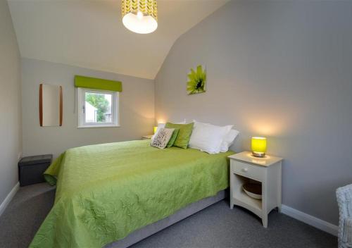 um quarto com uma cama verde e uma mesa de cabeceira em Lluesta Cottage em Abersoch