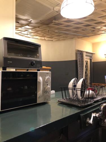 a kitchen counter with a microwave and dishes in a drying rack at tsubame-ya in Kyoto