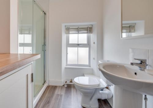 a white bathroom with a toilet and a sink at Bronwydd in Abersoch