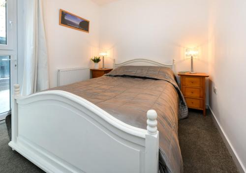 a bedroom with a white bed and two night stands at Y Cwtch in Llanbedrog