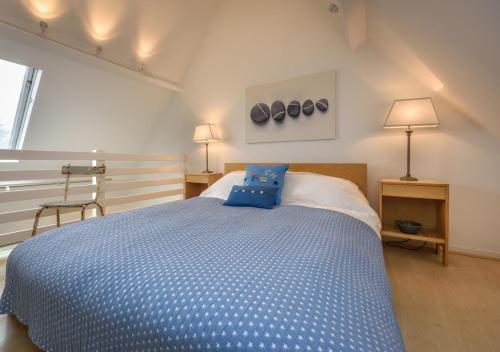 a bedroom with a bed with blue pillows on it at St Tudwals View in Abersoch