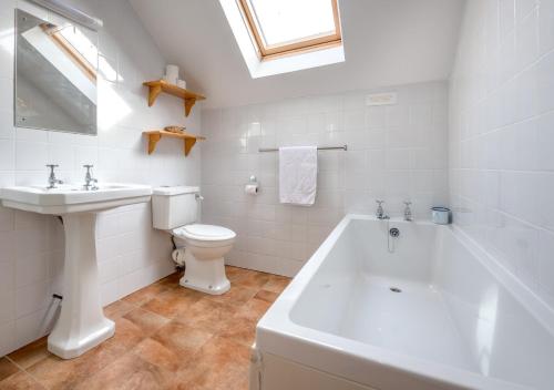 a bathroom with a white tub and a toilet and a sink at Bragdy Wern in Llanbedrog