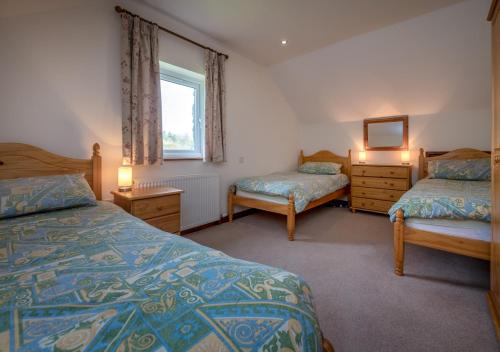 a bedroom with two beds and a mirror and a window at Bragdy Wern in Llanbedrog