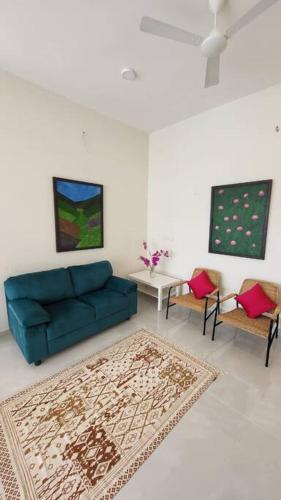 a living room with a blue couch and two chairs at Lucky Charm 2BHK Apartment - Muttukadu ECR in Chennai