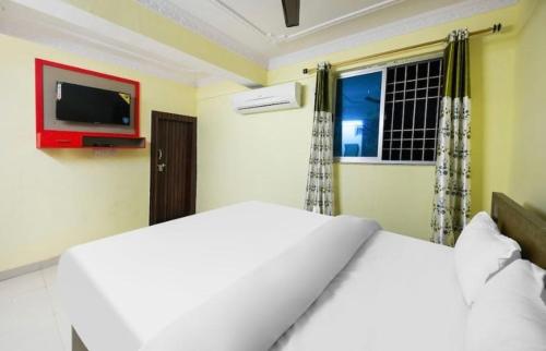 1 dormitorio con 1 cama blanca y TV en la pared en POP Oyo Flagship Moon Light Hotel, en Ranchi