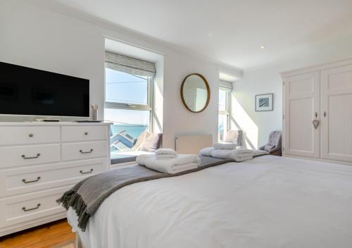um quarto branco com uma cama grande e uma televisão em Suffolk Cottage em Porthleven