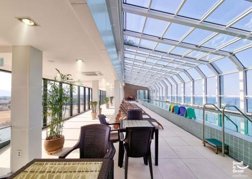 un bâtiment avec un plafond en verre, des tables et des chaises dans l'établissement Maple Beach Golf & Resort, à Gangneung