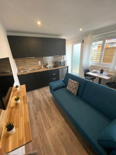 a living room with a blue couch and a table at Studio neuf à Bouguenais+terrasse+parking in Bouguenais