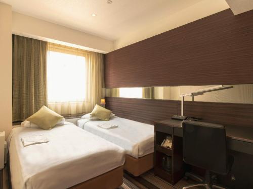 a hotel room with two beds and a desk at Hotel Brighton City Osaka Kitahama in Osaka