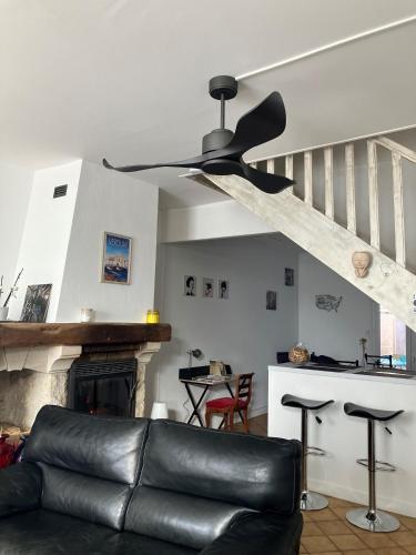 a black leather couch in a living room with a ceiling fan at Jolie, cozy, confortable maison de ville au calme à 5min du centre de Verdun, parking devant la maison in Belleville-sur-Meuse