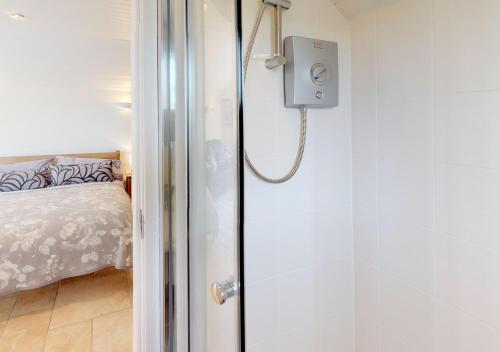 a shower in a room with a bed at Y Ddol Bach in Abersoch