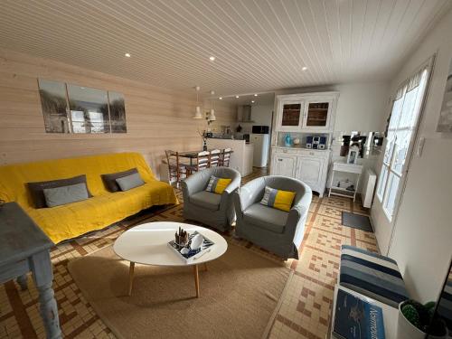 un salon avec un canapé jaune et une table dans l'établissement Maison Bord de Mer au Vieil 3 étoiles, à Noirmoutier-en-l'lle