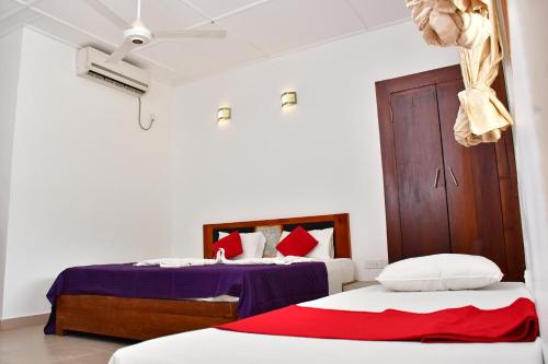 1 dormitorio con 2 camas y puerta de madera en Sea Way Hotel, en Nilaveli