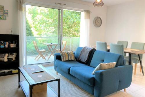 un salon avec un canapé bleu et une table dans l'établissement L'Amazone-Appart au calme avec balcon et parking, à Nantes