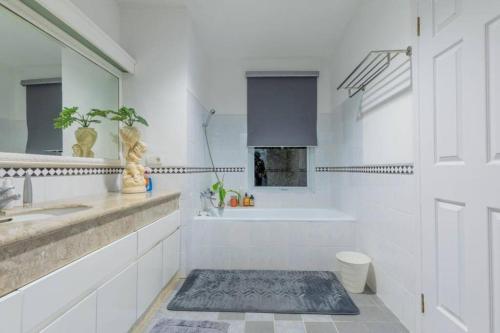 y baño blanco con bañera, lavamanos y bañera. en LaGita Carita Villa, en Pandegelang