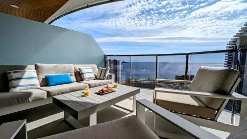 un soggiorno con divano e un tavolo sul balcone. di SUNSET WAVES luxury apartment a Benidorm