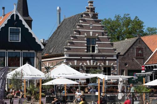 a group of tables with umbrellas in front of a building at Surla Houseboat De Saek with tender in Monnickendam