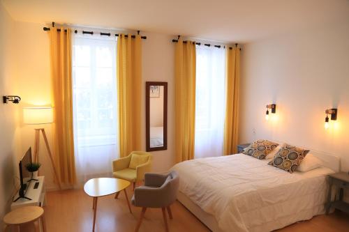 a bedroom with a bed and a chair and windows at Maison Candela in Argelès-Gazost