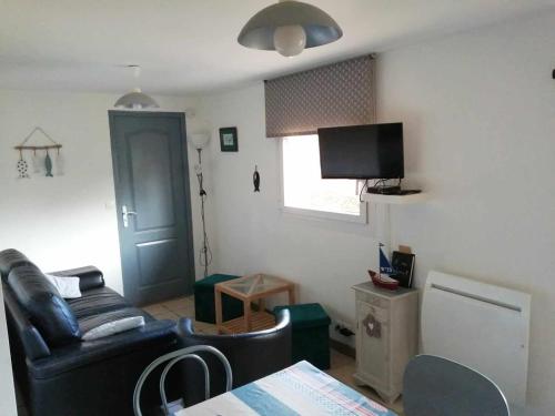 a living room with a black leather couch and a television at Au fil de l'eau in Conchy-sur-Canche