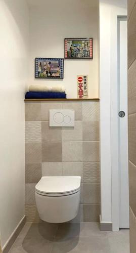 une salle de bains avec des toilettes et deux photos sur le mur. dans l'établissement 123 Honfleur, à Honfleur