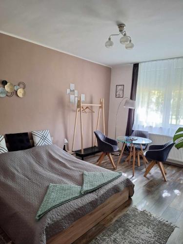 a bedroom with a bed and a table with chairs at Aréna Apartman in Kaposvár