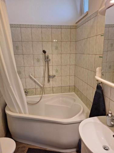 uma casa de banho com uma banheira, um WC e um lavatório. em Aréna Apartman em Kaposvár