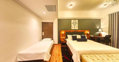 a hotel room with two beds and a desk at Covanro Sigiriya - Where Heritage Meets Luxury in Sigiriya