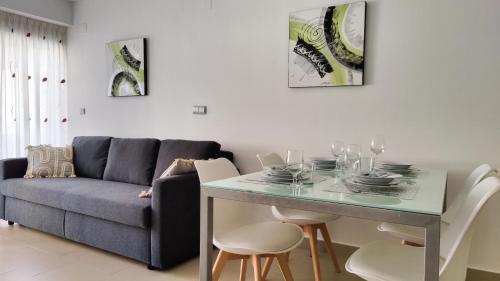 een woonkamer met een bank en een tafel met stoelen bij MIRADOR Poniente beach apartments in Benidorm