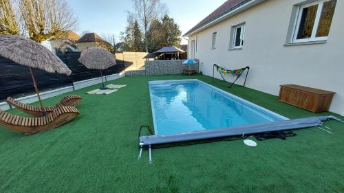 een achtertuin met een zwembad met stoelen en een parasol bij Maison neuve avec piscine, 10 couchages, tout confort in Granieu