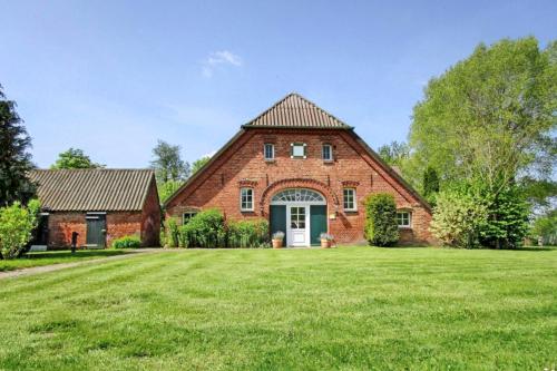 a large brick house with a large grass yard at Galerie Haus Wohnung 2 in Sehestedt