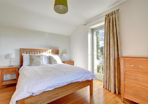 a bedroom with a large bed and a window at The Well House Trevisquite in Saint Tudy