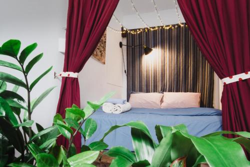 um quarto com uma cama com cortinas vermelhas e plantas em Bunker - The Writer's Loft em Ho Chi Minh