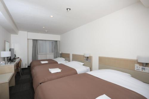 a hotel room with two beds and a desk at Sapporo Oriental Hotel in Sapporo