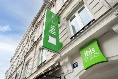 a building with two green signs on the side of it at ibis styles Paris Montmartre Batignolles in Paris