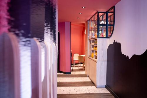a hallway with red walls and a table with chairs at ibis styles Paris Montmartre Batignolles in Paris