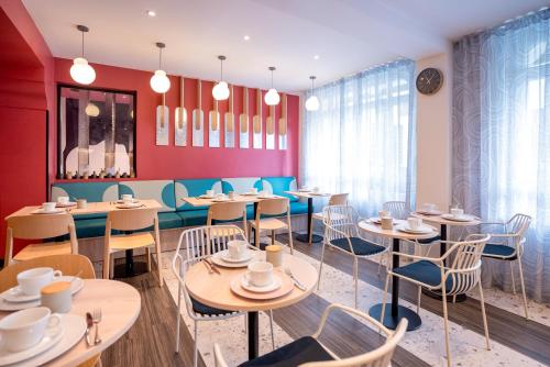 ibis styles Paris Montmartre Batignolles في باريس: غرفة طعام مع طاولات وكراسي ونوافذ
