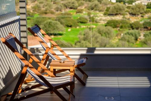 two wooden chairs sitting on a balcony with a window at Αntheon Apartment 3 in Agios Nikolaos