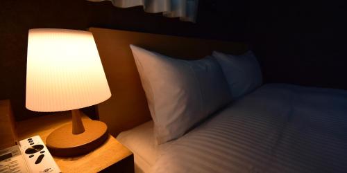 a bedroom with a bed with a lamp next to it at Rakuten STAY HOUSE Kujukuri Ichinomiya in Ichigaya