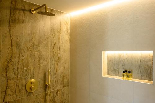 a bathroom with a shower with a stone wall at Αntheon Apartment 3 in Agios Nikolaos