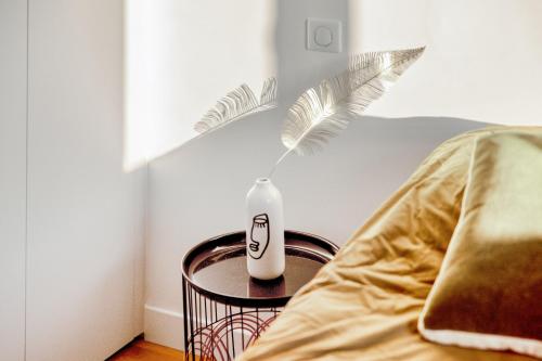 un vase assis sur une table à côté d'un lit dans l'établissement Appartement Loulib I Electio, à Nice
