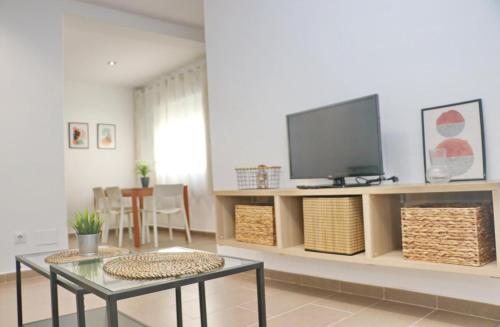 Una sala de estar con un televisor y una mesa. en Apartamento Goya, en Conil de la Frontera