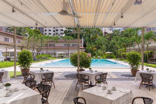 un restaurant avec des tables et des chaises ainsi qu'une piscine dans l'établissement Goodwood Park Hotel, à Singapour