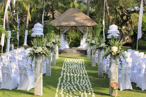 an aisle with white chairs and a gazebo at Legian Beach Hotel in Legian