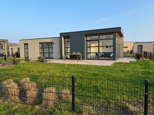 a modern house with a fence in front of it at Enkhuizer Strand Chalet Meeresbrise Dritte Reihe mit Zaun Haus Nr 251 in Enkhuizen
