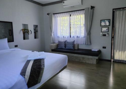 a bedroom with a bed and a window with a bench at Century Hotspring Resort in Phra Chedi Sam Ong