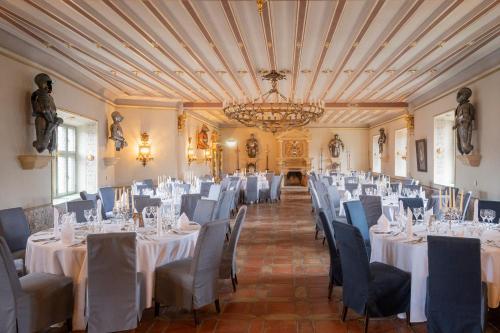 um quarto com mesas e cadeiras brancas e um lustre em Burg Rabenstein em Kirchahorn