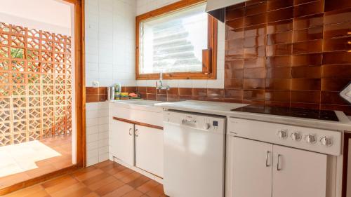 a kitchen with white cabinets and a window at LES TEULADES 3 in Tamariu