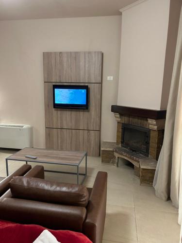 sala de estar con sofá, mesa y TV en Iris Flower Hotel, en Jezzîne