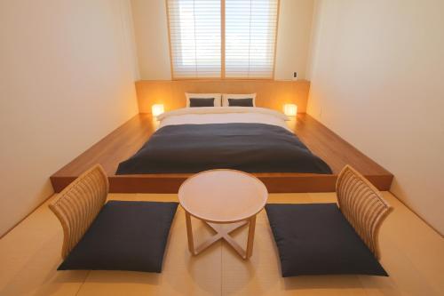 um quarto com uma cama, uma mesa e cadeiras em Ishigakijima Hotel Cucule em Ishigaki Island