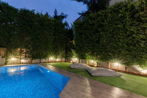 a swimming pool in the middle of a yard at night at Athenian Grand Riviera Villa in Athens
